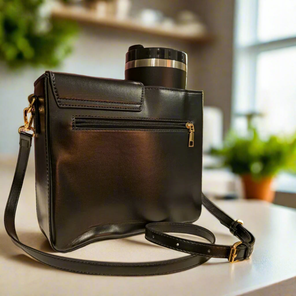 Black leather handbag with a floral arrangement and decorative items in the background