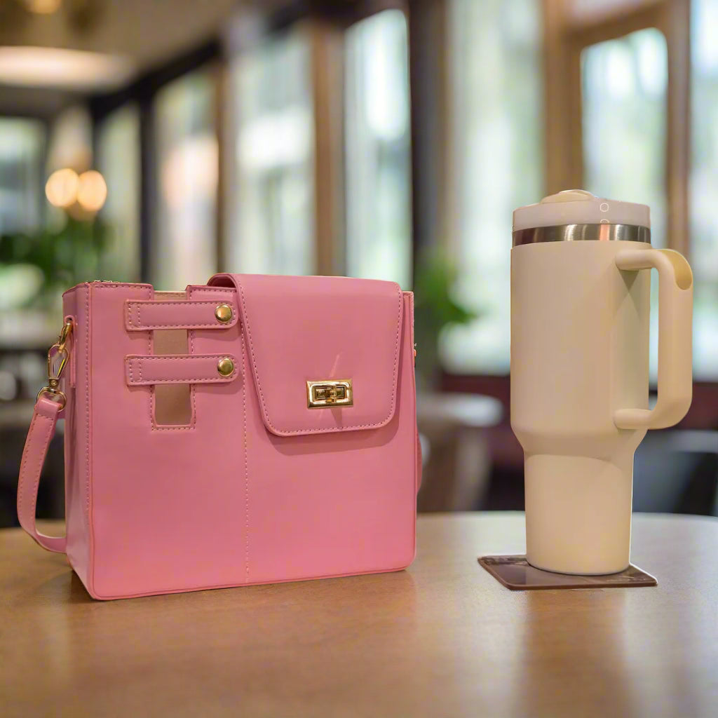 Pink handbag next to a white mug with a floral arrangement on a patterned background