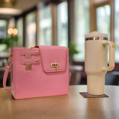 Pink handbag next to a white mug with a floral arrangement on a patterned background