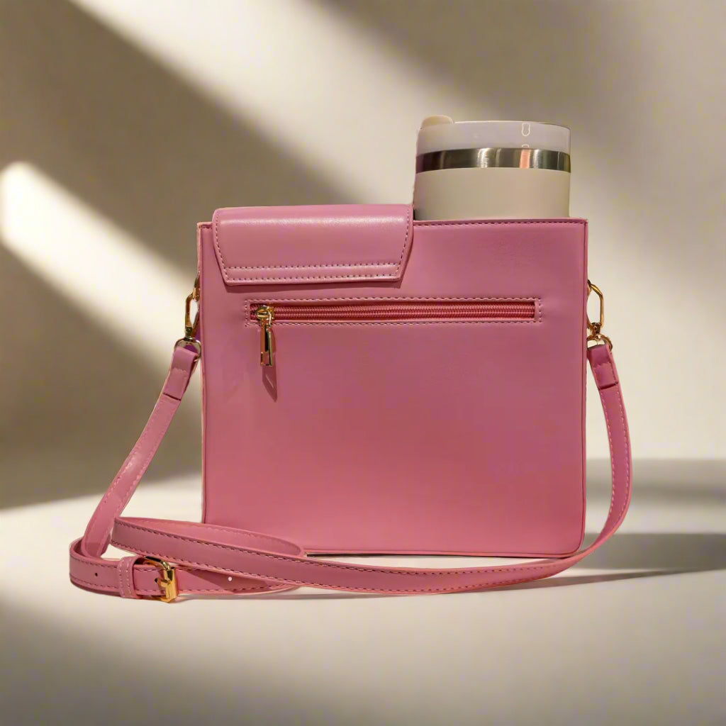Pink handbag with a gold clasp on a white surface with a patterned purple background